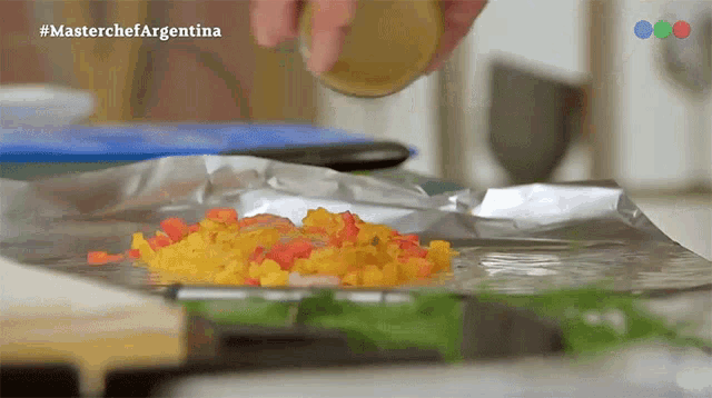 a close up of a person sprinkling seasoning on a foil covered item with the hashtag masterchefargentina