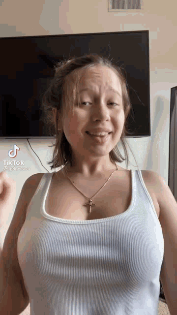 a woman in a white tank top is standing in front of a tv .