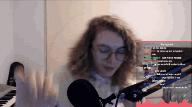 a girl with glasses is playing a piano in front of a microphone while a stream is being watched