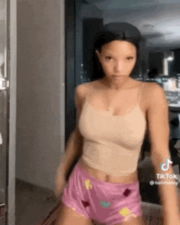 a woman in a tan tank top and pink shorts is dancing .