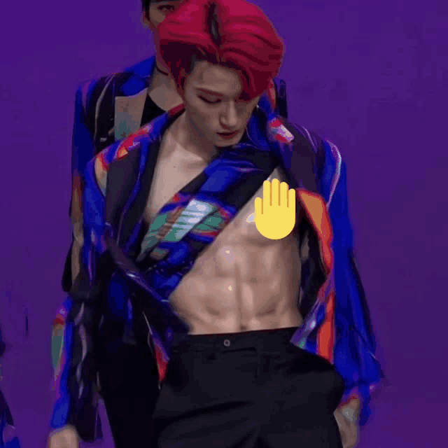 a man with red hair is showing off his muscles while wearing a colorful shirt and black pants .