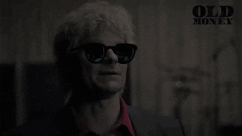 a man with a mullet and sunglasses is wearing a suit .