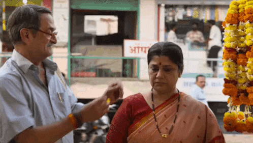 a man and woman are standing next to each other in front of a sign that says ' aar ' on it .