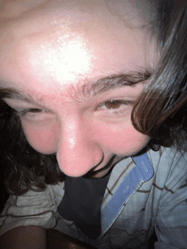 a close up of a person 's face with a plaid shirt