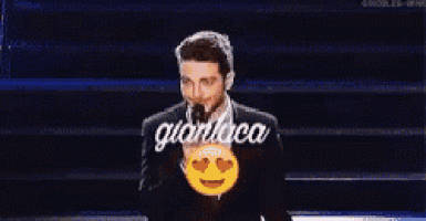 a man in a suit and tie is holding a smiley face with hearts on his eyes .