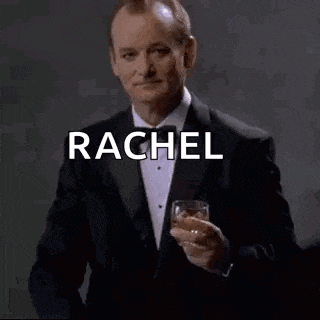 a man in a tuxedo is holding a glass of whiskey and pointing at the camera .