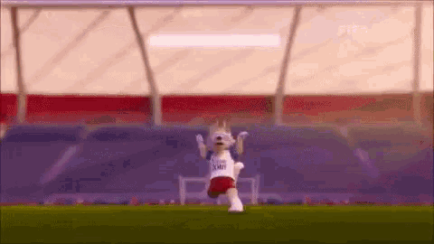 a mascot is standing on a soccer field with his arms in the air .