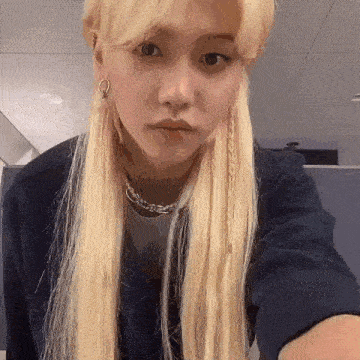 a woman with blonde hair is taking a selfie with her phone .