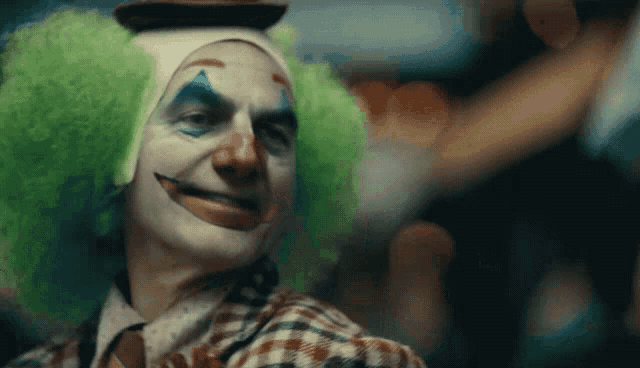 a close up of a clown with green wigs and a hat