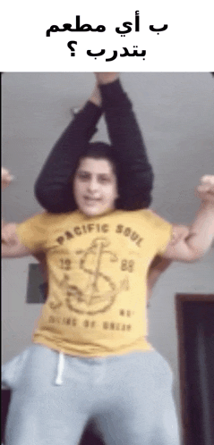 a man wearing a pacific soul t-shirt is holding another man 's legs over his head