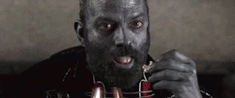 a man with a beard is eating a piece of meat