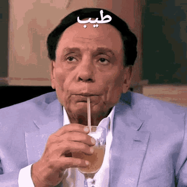 a man in a suit drinks through a straw from a wine glass