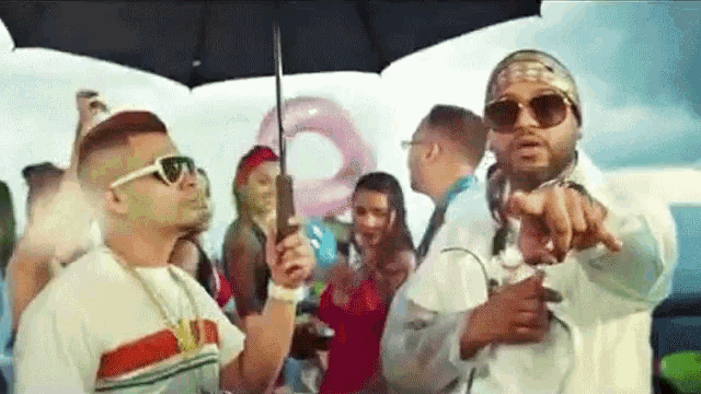 a man is holding an umbrella while standing next to another man .