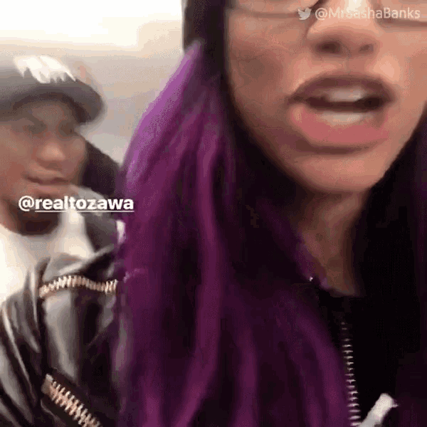 a woman with purple hair and glasses is talking to a man
