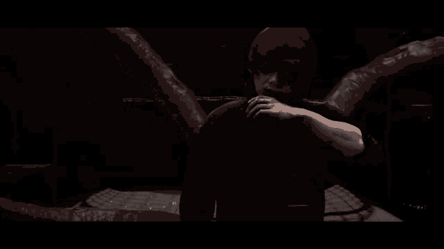 a man in a black shirt is standing in a dark room with a monster in the background