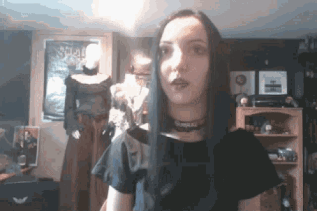 a woman wearing a choker and a black shirt is standing in front of a sign that says ' skull ' on it