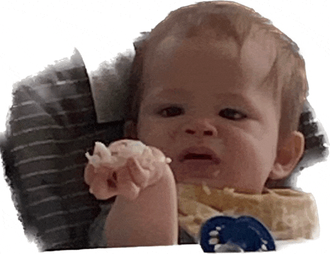 a baby with a pacifier is holding something in his hand and making a funny face