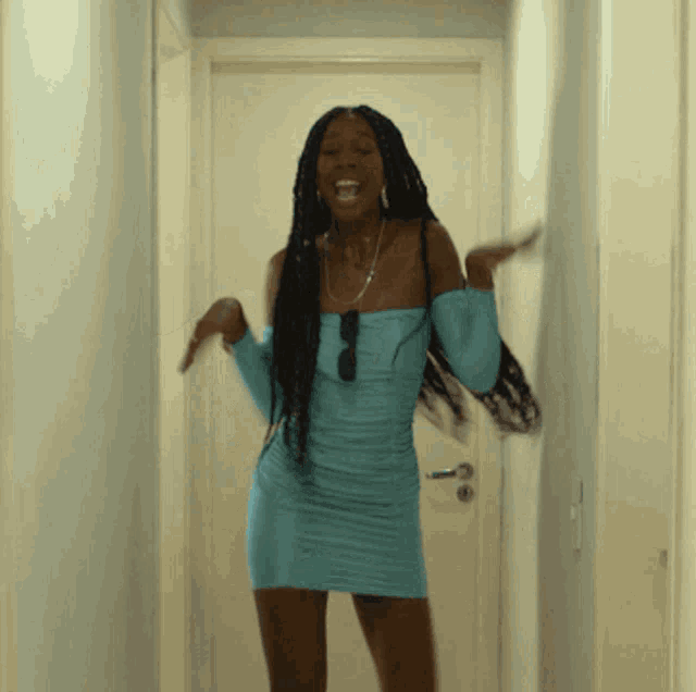 a woman in a blue dress stands in a hallway
