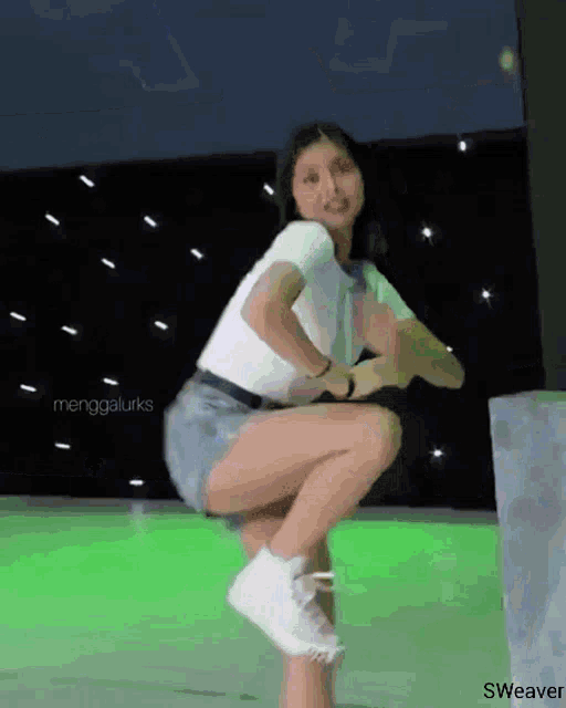 a woman is squatting down in front of a green background with the words sweaver on the bottom