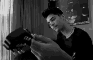 a black and white photo of a young man holding a guitar .