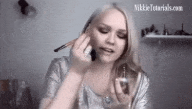 a woman is applying makeup with the website nikkietutorials.com visible in the background