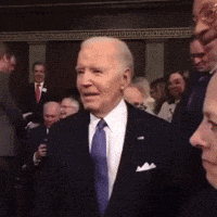 a man in a suit and tie stands in front of a crowd