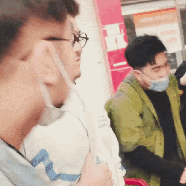 a man wearing glasses and a face mask stands in front of a sign that says ' a ' on it