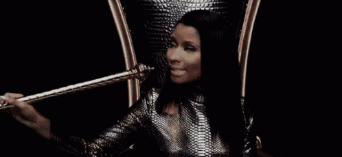 a woman is sitting in a chair holding a gold cane