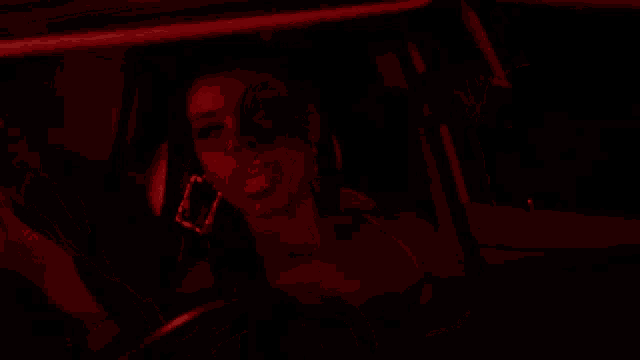 a woman is sitting in a car with red lights on