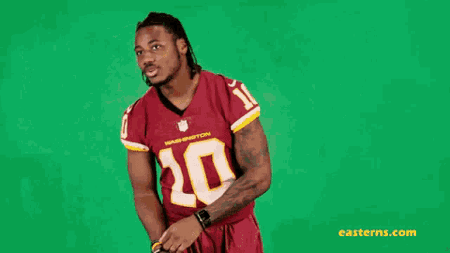 a man wearing a washington redskins jersey is standing in front of a green background