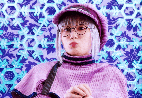 a woman wearing glasses and a purple hat making a face