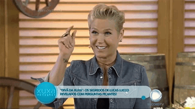 a woman in a denim jacket is smiling and pointing