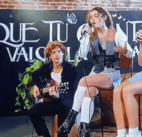 a man is playing a guitar and a woman is singing into a microphone