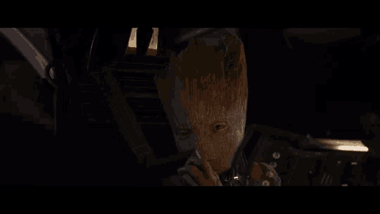 groot is smoking a cigarette in a dark room .
