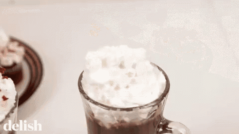 a person is adding red velvet crumbs to a cup of hot chocolate .