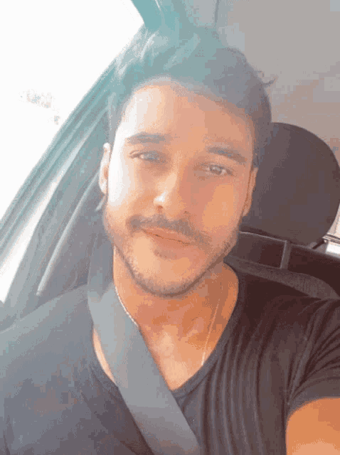 a man with a beard is wearing a black shirt and a black seat belt
