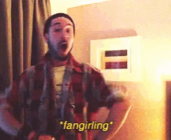 a man in a plaid shirt says " fangirling " in a room