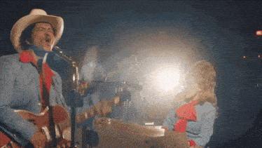 a man in a cowboy hat sings into a microphone