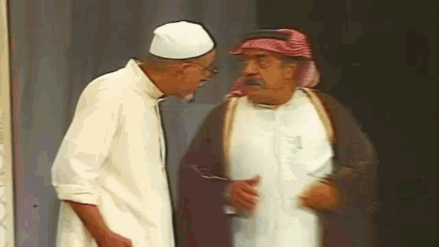 a man in a white hat is talking to another man in a brown robe