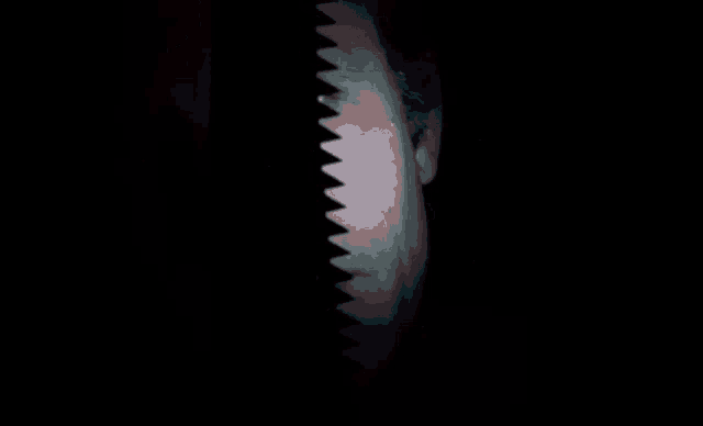 a close up of a man 's face with a saw blade behind it