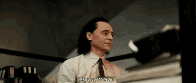 a man in a white shirt and tie is standing in front of a computer and talking .
