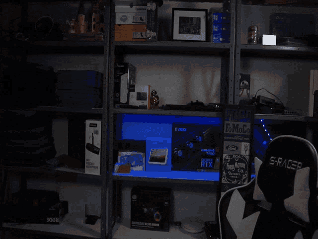 a s-racer chair sits in a dark room surrounded by shelves of electronics