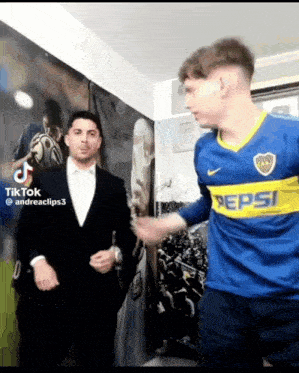 a man in a suit is standing next to a man in a blue pepsi shirt