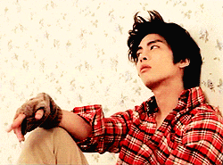 a man in a plaid shirt is sitting in front of a wall