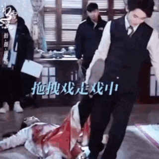 a man standing next to a woman laying on the floor .