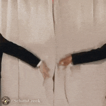 a woman in a white dress is behind a white curtain being pulled open by two men .