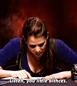 a woman is sitting at a table with her hands on a piece of paper and says `` listen , you little bitches . ''