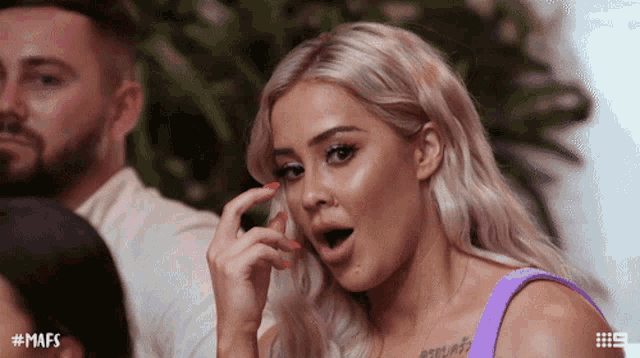 a woman in a purple tank top has a tattoo on her chest that says feelings