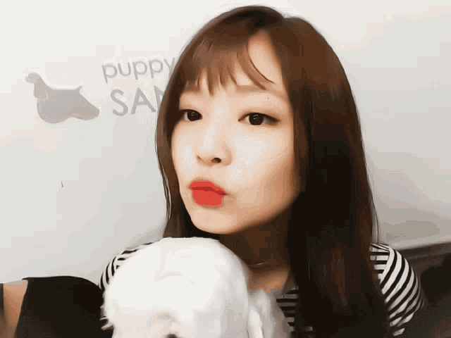 a woman holds a small white dog in front of a puppy san sign