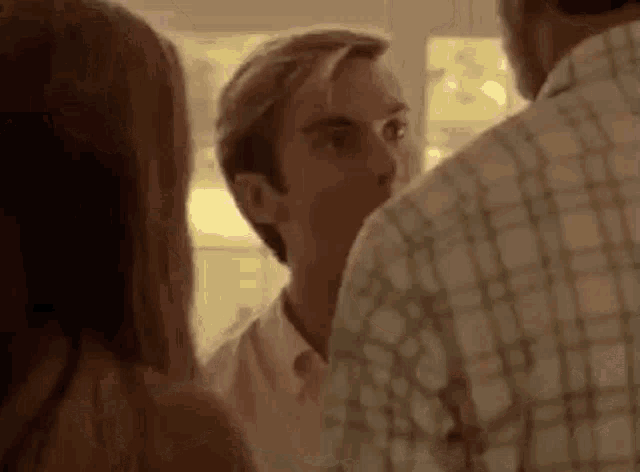 a man and a woman are standing next to each other in a room and talking to each other .